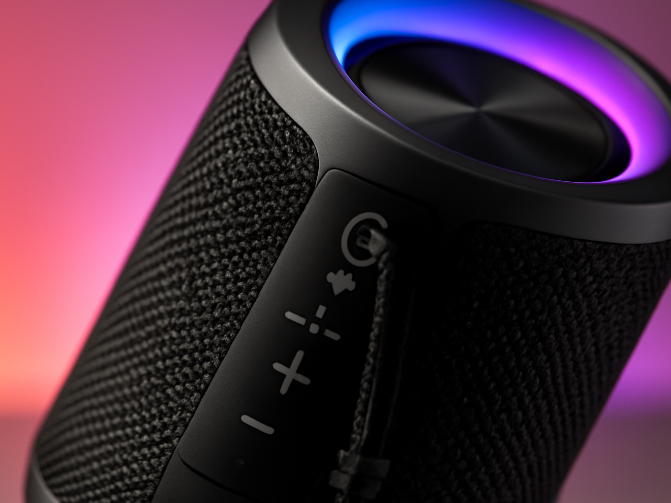 Close-up of wireless speaker showing fabric grille texture with soft RGB light glow in background